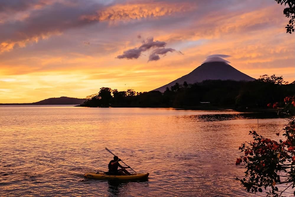 Kayaker paddling Lake Nicaragua at sunset with Volcán Concepción behind